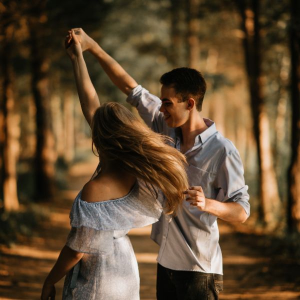 An image of a husband and wife dancing in a forest.