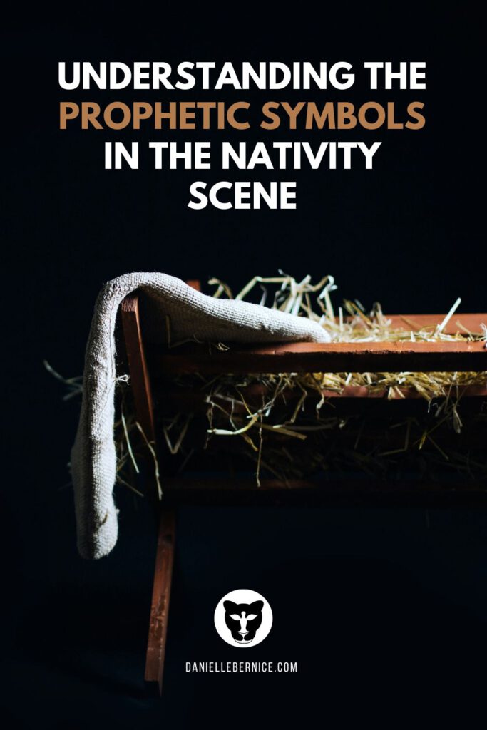 Understanding the prophetic symbols in the nativity scene. The photo shows an illuminated wooden manger with hay and a linen cloth hanging from it. DanielleBernice.com