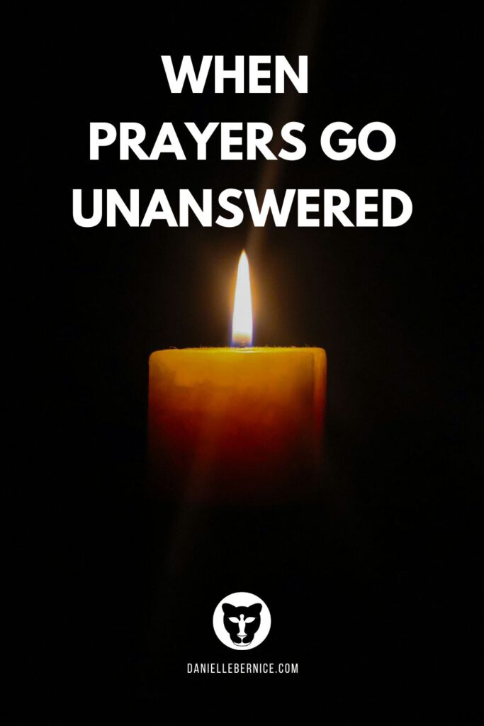 A candle light in complete darkness. Overlay reads: When prayers go unanswered. DanielleBernice.com