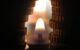 Image of a pile of coins in the dark in front of a candle.