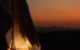 A photo of a tent with a glowing light in it, out of focus, while the sunrise in the background is in focus