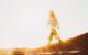 Photo of a woman walking in the desert into a bright light
